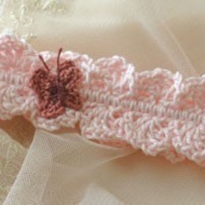 Pu&ograve; includere: Un delicato cerchietto rosa lavorato a uncinetto con un piccolo ornamento a forma di farfalla rosa.