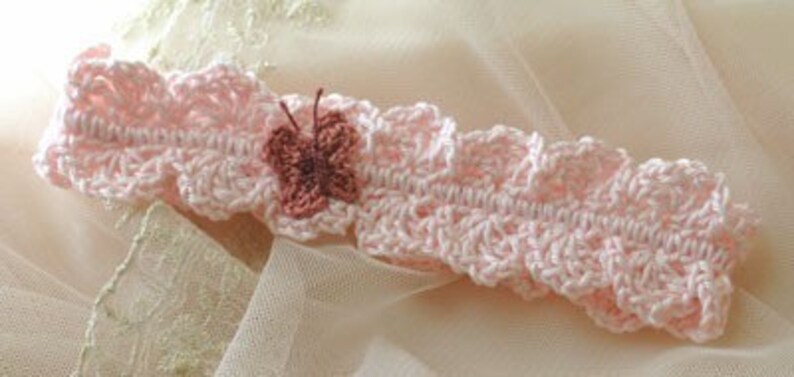 Pu&ograve; includere: Un delicato cerchietto rosa lavorato a uncinetto con un piccolo ornamento a forma di farfalla rosa.
