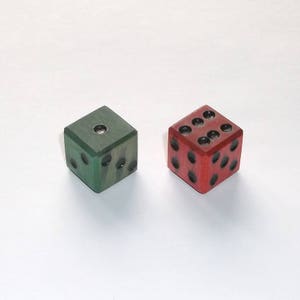 May include: Two wooden dice, one green and one red, with black dots. The dice are used for games and crafts.