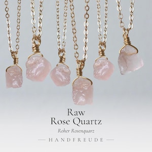 Può includere: Sei collane con pendenti in quarzo rosa grezzo di colore rosa pallido, sospesi a sottili catene in metallo dorato. Ogni pietra è avvolta in un filo metallico dorato sulla parte superiore. Il testo recita: Raw Rose Quartz, Roher Rosenquarz, HANDFREUDE.