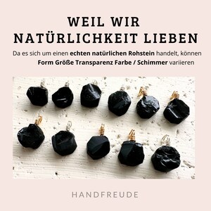 May include: Ten black gemstone pendants with gold wire wraps. The text "WEIL WIR NAT&Uuml;RLICHKEIT LIEBEN" is at the top of the image. The text "Da es sich um einen echten nat&uuml;rlichen Rohstein handelt, k&ouml;nnen Form Gr&ouml;&szlig;e Transparenz Farbe / Schimmer variieren" is below the pendants. The text "HANDFREUDE" is at the bottom of the image.
