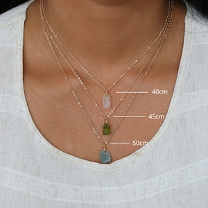 May include: Three gold chain necklaces with different lengths: 40cm, 45cm, and 50cm. Each necklace features a different coloured gemstone pendant: pink, green, and blue.