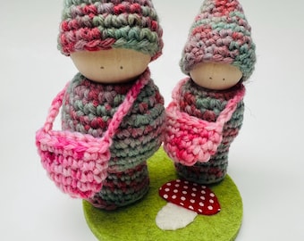 A set of two wood peg dolls in wool outfits, measure 5" and 4" tall.