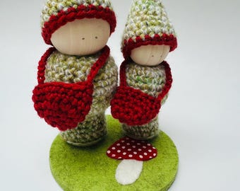 A set of two wood peg dolls in wool outfits, measure 5" and 4" tall.