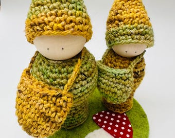 A set of two wood peg dolls in wool outfits, measure 5" and 4" tall.
