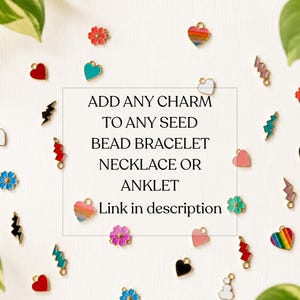 May include: A collection of small metal enamel charms in shapes of hearts, flowers, and lightning bolts, scattered around the text: ADD ANY CHARM TO ANY SEED BEAD BRACELET NECKLACE OR ANKLET Link in description.