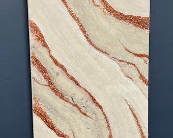 Puede incluir: Arte mural abstracto con un fondo crema y blanco, y acentos brillantes de color cobre. La pieza rectangular está montada en una pared azul oscuro, con una lámpara de pared dorada encima.