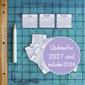 Op de afbeelding: Een verzameling kleine, witte papieren kalenderpagina's voor de maanden januari, september, november, augustus, april, februari en oktober. Een lichtgekleurd hobbymes en een houten liniaal van maximaal 29 centimeter liggen in de buurt.