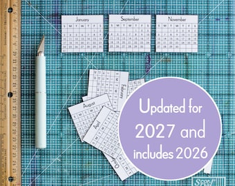 May include: A collection of small, white paper calendar pages for the months of January, September, November, August, April, February, and October. A light-colored craft knife and a wooden ruler measuring up to 29 centimeters are positioned nearby.