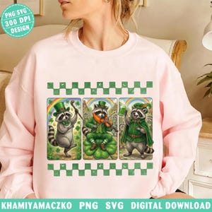 Peut inclure: Un sweat-shirt rose clair avec un motif de la Saint-Patrick. Il présente trois ratons laveurs de dessins animés en tenues vertes, chacun avec une activité différente : l'un avec une canne, l'autre jouant du violon et le troisième tenant une boisson verte. Le motif comprend des arcs-en-ciel et des trèfles.