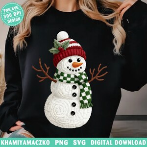 Peut inclure: Sweat-shirt noir avec un motif de bonhomme de neige. Le bonhomme de neige porte un chapeau rayé rouge et blanc, une écharpe à carreaux verts et blancs et des bras en brindilles. Il a un nez en carotte et des yeux et une bouche en boutons noirs. Le texte "PNG SVG 300 DPI DESIGN" est en haut à gauche.