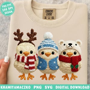 Könnte beinhalten: Cremefarbenes Sweatshirt mit gesticktem Design von drei Küken in Winterkleidung. Ein Küken trägt Rentiergeweih und einen rot-weißen Schal, ein anderes eine blaue Mütze und Weste, und das letzte einen Bärenhut und einen roten Schal. Der Entwurf enthält den Text "KHAMIYAMACZKO PNG SVG DIGITAL DOWNLOAD".