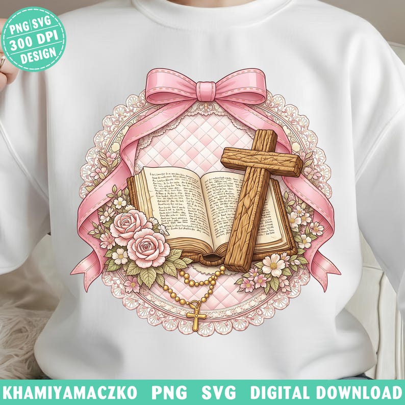 May include: White sweatshirt featuring a religious design. The design includes a wooden cross, an open book, pink roses, a rosary, and a pink bow. The design is surrounded by a pink lace-like border.