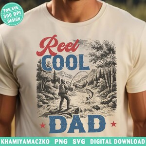 May include: A cream-coloured t-shirt with a graphic of a fisherman catching a fish, and the words "Reel Cool Dad" in red and blue. The design includes a mountain and river scene. The shirt is a PNG SVG 300 DPI design.