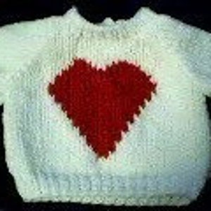 May include: White knitted baby sweater with a red heart design on the front.