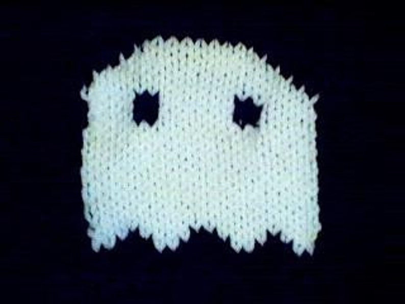 May include: White knitted ghost with two black eyes. The ghost is a simple design with a rounded top and a wavy bottom.