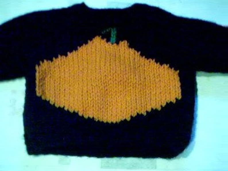 May include: A dark blue knitted jumper with a large orange pumpkin design on the front.