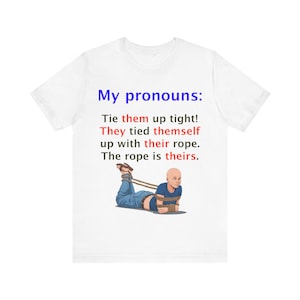 Peut inclure: Un t-shirt blanc avec le texte "Mes pronoms : Attachez-les bien ! Ils se sont attachés avec leur corde. La corde est à eux."