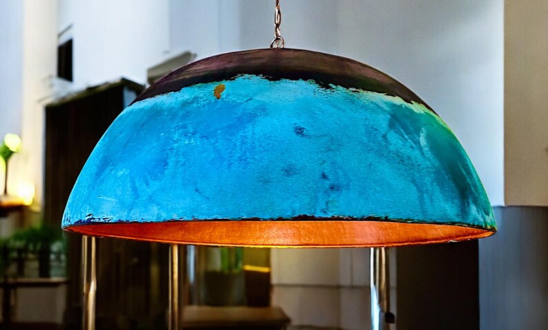 May include: A large, dome-shaped pendant light fixture with a blue and copper finish. The light is hanging from a chain and has a warm, inviting glow.