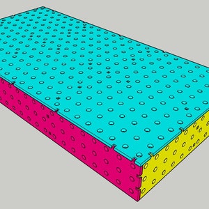 Puede incluir: Una plataforma rectangular con una parte superior azul y lados amarillos y rosados. La parte superior está cubierta por una cuadrícula de pequeños círculos.