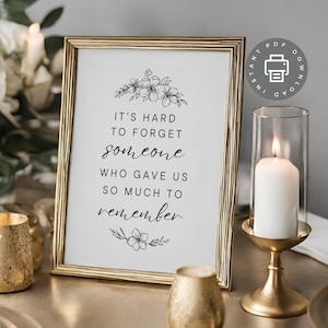May include: A gold-framed printable sign with a black floral design and the text "It's hard to forget someone who gave us so much to remember."