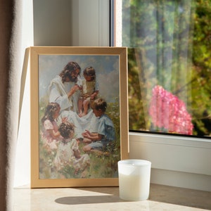Pode incluir: Uma pintura emoldurada que retrata Jesus cercado por crian&ccedil;as em um campo. A pintura est&aacute; em uma moldura de madeira clara e est&aacute; pendurada em uma parede ao lado de uma janela. Uma vela branca est&aacute; sentada em uma mesa em frente &agrave; pintura.