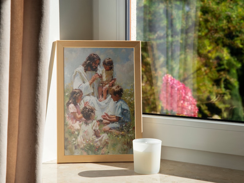 Pode incluir: Uma pintura emoldurada que retrata Jesus cercado por crian&ccedil;as em um campo. A pintura est&aacute; em uma moldura de madeira clara e est&aacute; pendurada em uma parede ao lado de uma janela. Uma vela branca est&aacute; sentada em uma mesa em frente &agrave; pintura.