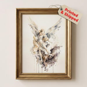 May include: A framed watercolour print depicting an angel with large wings holding a sword and standing over a dark figure. The artwork features muted tones of gold, brown, and grey. A beige tag attached to the frame displays the text Printed & Shipped.