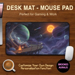 Pode incluir: Tapete de mesa retangular com um design temático espacial apresentando um astronauta relaxando perto de uma fogueira, com planetas e estrelas ao fundo. O tapete tem o texto "DESK MAT - MOUSE PAD" e "Customize Your Own Design". Um mouse branco e uma xícara de café também são visíveis.