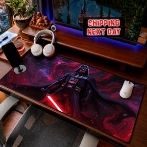 Könnte beinhalten: Ein rechteckiges Mauspad mit Darth Vader, der ein rotes Lichtschwert vor einem roten und lila Weltraumhintergrund hält. Eine weiße Maus befindet sich auf der rechten Seite des Pads. Das Pad liegt auf einem Holzschreibtisch.