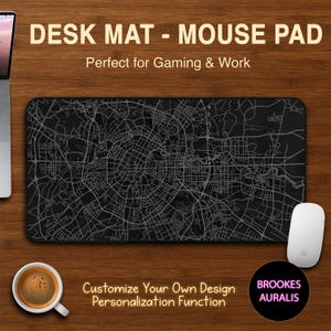 May include: Black desk mat with a detailed city map design. The mat is rectangular and features the text "DESK MAT - MOUSE PAD" and "Perfect for Gaming & Work". A white mouse and a cup of coffee are also visible on the wooden surface.