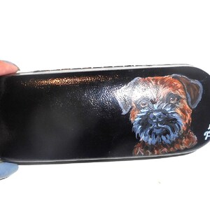May include: Black leather eyeglasses case with a hand-painted portrait of a brown and white dog. The dog's name, "Brody", is written in white on the case.