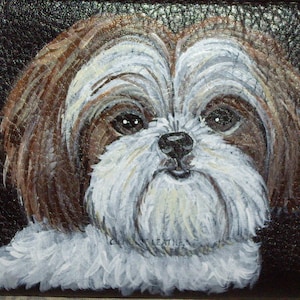 May include: A hand-painted portrait of a Shih Tzu dog on a black leather background. The dog has brown and white fur and is looking directly at the viewer.