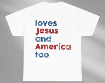 May include: White t-shirt with the text "loves Jesus and America too" in blue and red lettering. The text is arranged vertically on the front of the shirt.