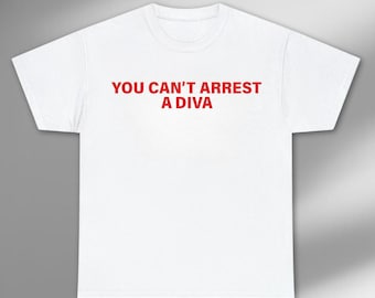 May include: White t-shirt with the red text "YOU CAN'T ARREST A DIVA". The shirt has short sleeves and a crew neck. The text is centered on the front of the shirt.
