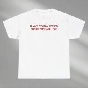 May include: White t-shirt with the red text "I HAVE TO SAY WEIRD STUFF OR I WILL DIE" printed across the chest. The shirt has a crew neck and short sleeves. The fabric appears to be a soft cotton blend.