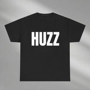 May include: Black t-shirt with the word "HUZZ" printed in white on the front.