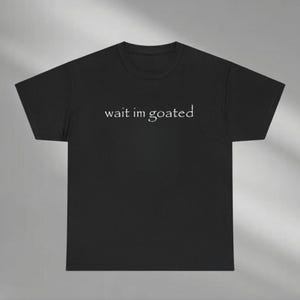 a black t - shirt that says wait i'm goated