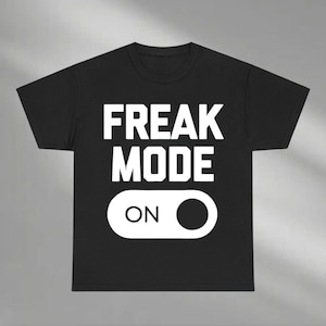 May include: Black t-shirt with the words "FREAK MODE" in large white capital letters. Below the text is a white graphic of an on/off switch with the word "ON" and a black circle.