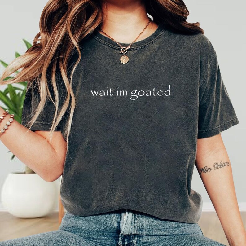 a woman wearing a t - shirt that says wait in goated