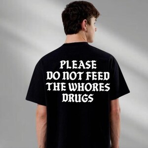 a man wearing a t - shirt that says please do not feed the whores