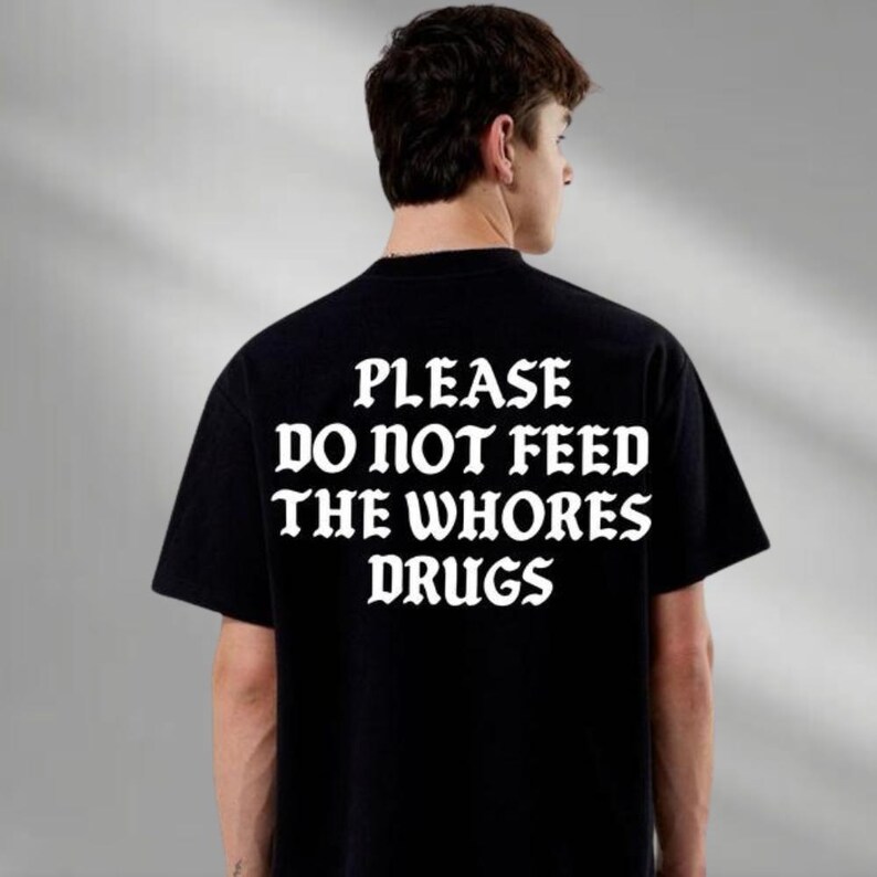 a man wearing a t - shirt that says please do not feed the whores