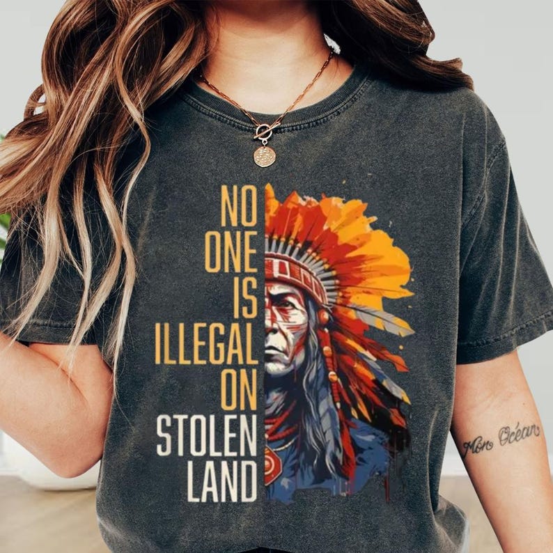 a woman wearing a t - shirt that says no one is illegal on stolen land