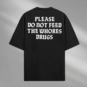 a black t - shirt that says please do not feed the whores drugs