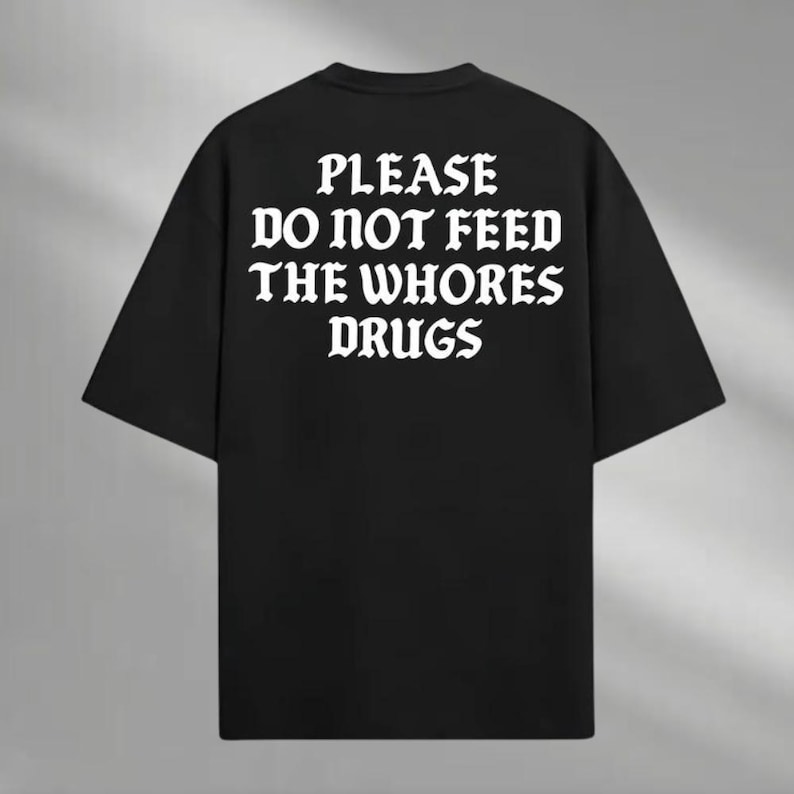 a black t - shirt that says please do not feed the whores drugs