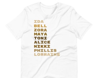 May include: White t-shirt with a vertical list of names in brown and gold lettering: Ida Bell, Zora, Maya, Toni, Alice, Nikki, Phillis, Lorraine.