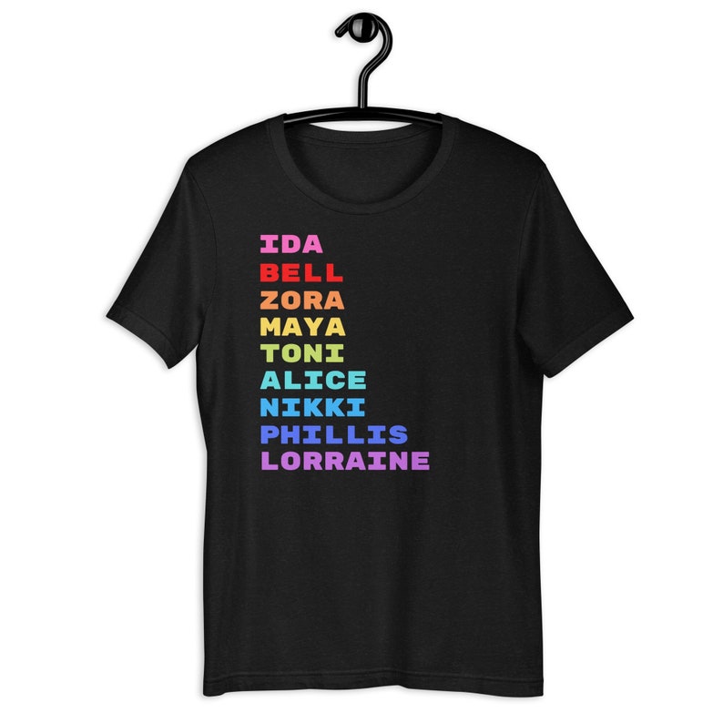 K&ouml;nnte beinhalten: Schwarzes T-Shirt mit einer senkrechten Liste von Namen in Regenbogenfarben: Ida Bell, Zora, Maya, Toni, Alice, Nikki, Phillis, Lorraine.