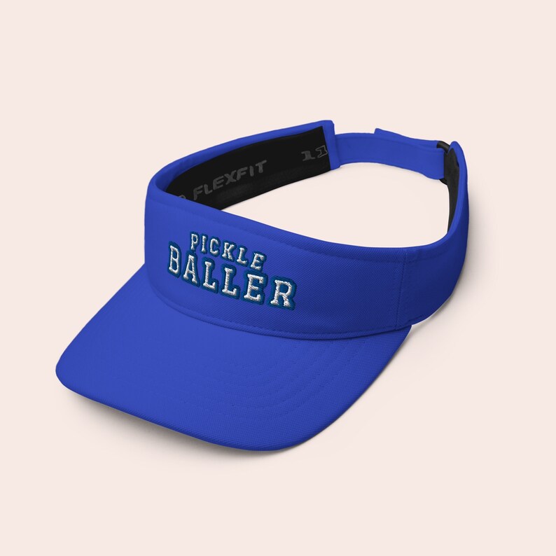 K&ouml;nnte beinhalten: K&ouml;nigsblaue Visier mit einem wei&szlig;en verstellbaren Band und dem Text "PICKLE BALLER", der in Wei&szlig; und Blau gestickt ist.
