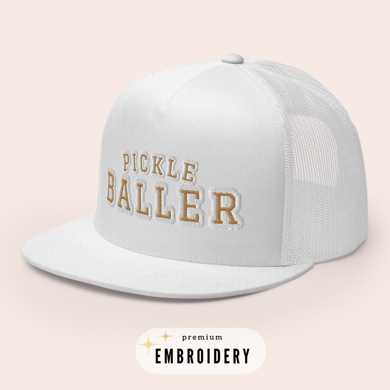 May include: White trucker hat with a brown embroidered design that says "Pickle Baller" with the words "premium embroidery" below the design.