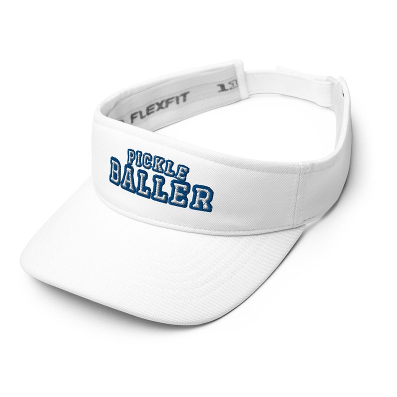 K&ouml;nnte beinhalten: Wei&szlig;er Visier mit einem blauen gestickten Logo, auf dem vorne "Pickle Baller" steht. Der Visier hat ein verstellbares schwarzes Band mit dem aufgedruckten Wort "Flexfit".